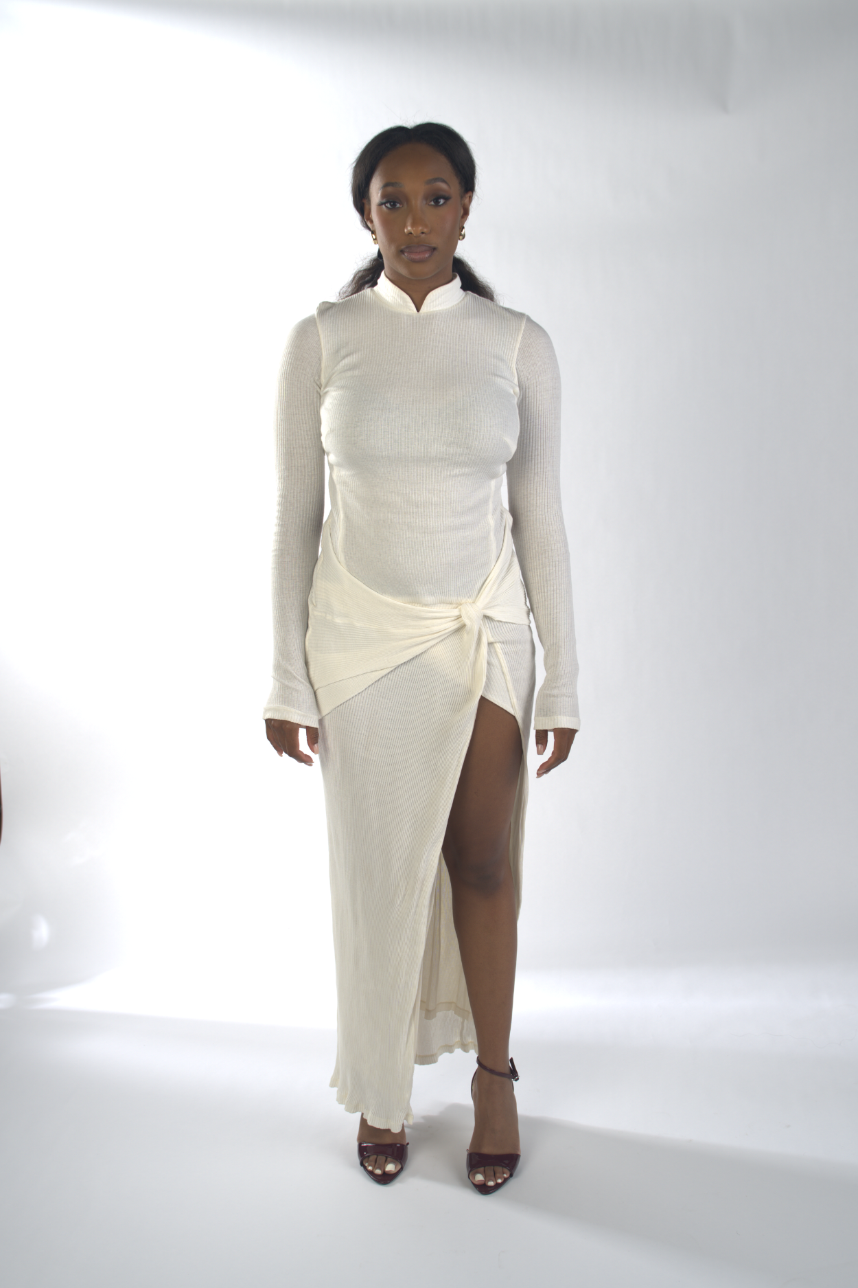 Woman wearing a white outfit with a high slit on a white background